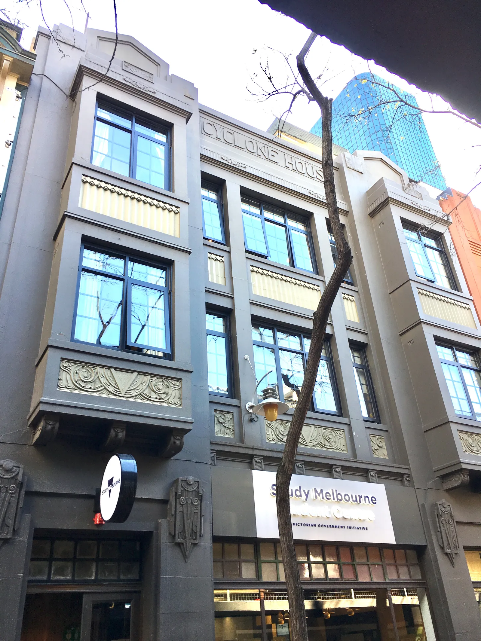 A narrow grey building with bay windows and the words Cyclone House across its front.